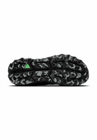 Suela de zapato atlético negra con un diseño resistente que presenta patrones elevados en tonos de gris y un acento verde. El caucho texturizado proporciona agarre.