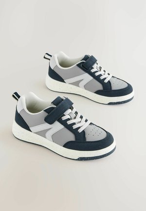 Sneakers navy e grigi con strappo in velcro, dotati di una suola maculata, tessuto testurizzato e lacci e dettagli bianchi a contrasto.