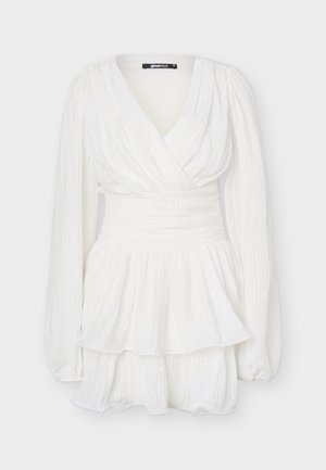 Λευκό φόρεμα με μακριά μανίκια, βαθύ V-ντεκολτέ, ζωνάκι στη μέση, υφασμάτινη υφή και φούστα με στρώσεις βολάν.