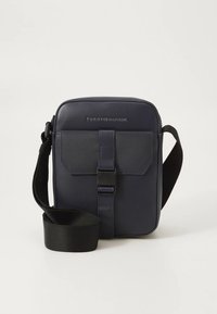 Geantă crossbody albastru închis din piele sintetică, cu clapetă frontală prevăzută cu închidere cu cataramă și curea reglabilă din material textil.