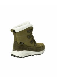 Bottines en suede vert avec un collier en fausse fourrure blanche, des lacets et une semelle en caoutchouc texturée. Présente le logo et un design étanche.