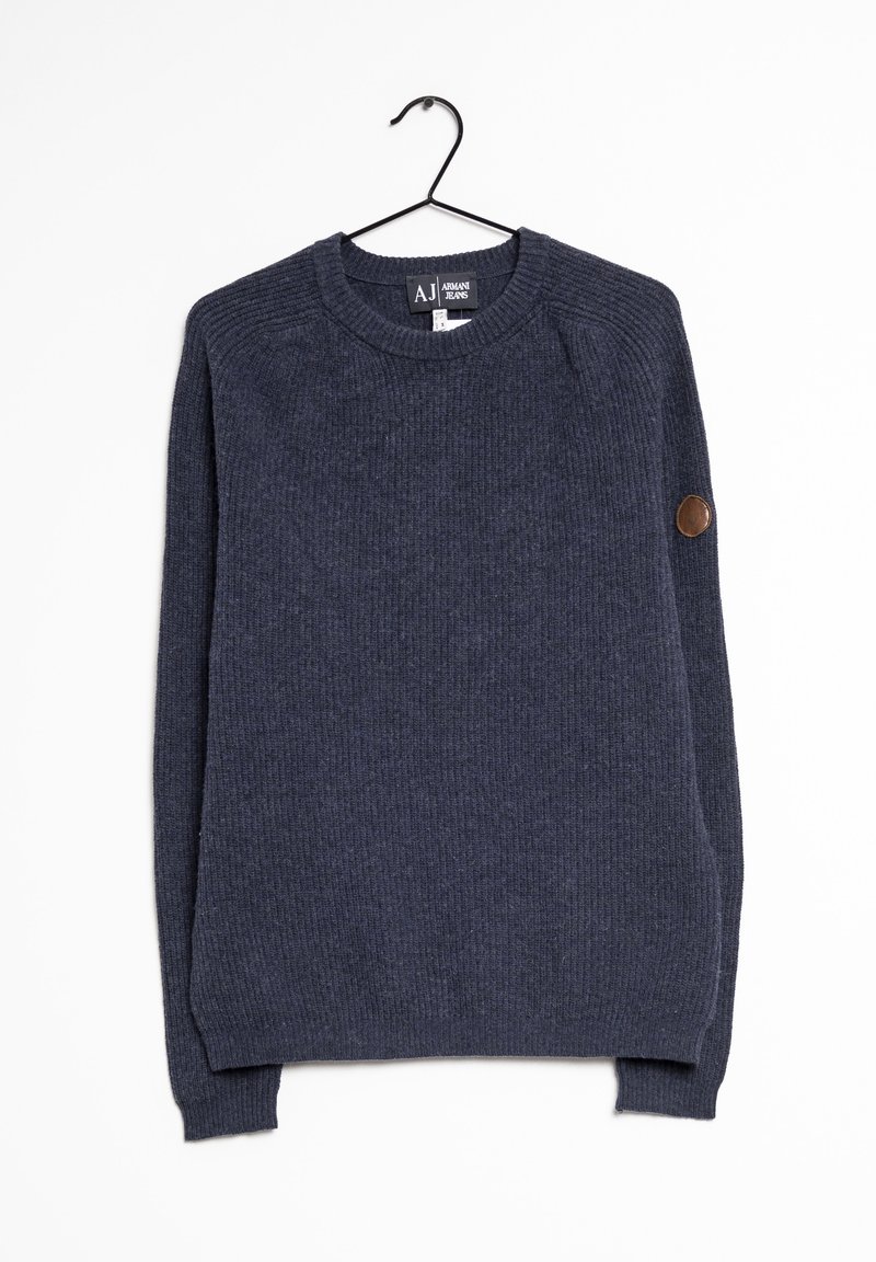 Sweat-shirt bleu foncé en maille côtelée à manches longues suspendu sur un cintre noir, avec un écusson en cuir rond sur le coude gauche.
