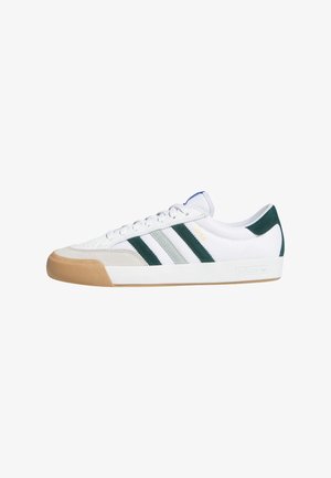 Zapatilla deportiva blanca con rayas verdes y grises, detalles en ante y parte superior de malla texturizada. Cuenta con suela de goma y cierre de cordones.