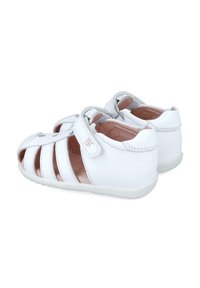 Sandalias de cuero blanco con diseño recortado, correa ajustable, forro interior suave y suela de goma blanca flexible.