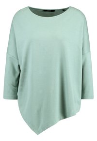 Maglia oversize verde menta con un motivo geometrico testurizzato, maniche corte larghe e un orlo asimmetrico, che offre una silhouette rilassata.