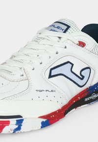 Άσπρο αθλητικό παπούτσι με λευκά κορδόνια, μπλε και κόκκινη σόλα, το κείμενο «Top-Flex» και ένα μπλε περιγραμματικό λογότυπο αριθμού στο πλάι.
