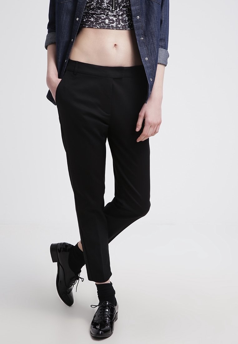 Svarta skräddarsydda byxor med slim fit, slät textur och kort längd, parat med blanka svarta finskor och en denimskjorta.