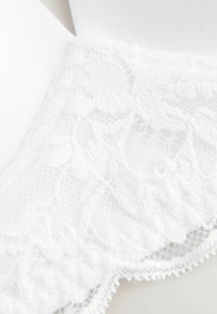Reggiseno bianco con dettagli in pizzo intricati lungo i bordi, texture in tessuto morbido e orlo scallop. Design semplice ed elegante.
