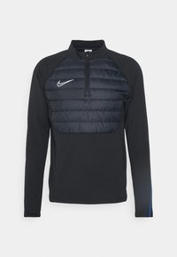 Czarny polar średniej grubości Nike ma pikowaną panel na klatce piersiowej, wysoki kołnierz oraz długie rękawy z niebieskim akcentem na mankietach.