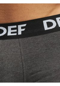 Gray cotton boxer shorts with a black elastic waistband featuring white "DEF" lettering. The fabric has a smooth, ribbed texture.