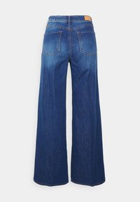 Vidjeans i djupblått med vida ben, hög midja, två bakfickor och en brun läderlapp vid midjebandet.