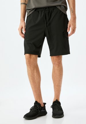 Sorte atletiske shorts med elastisk talje og snøre, med en sidelomme og glat, letvægts stof.