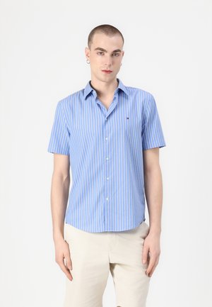 Short-sleeve button-up shirt in light blue with white vertical stripes. Features a classic collar and small logo on the chest.