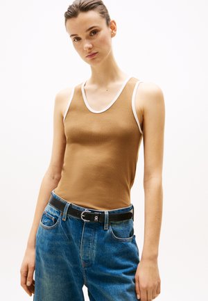 Brun ribbet tanktop med hvit kant, parret med høydefinerte blå denimjeans og et svart belte. Enkel, tettsittende design.