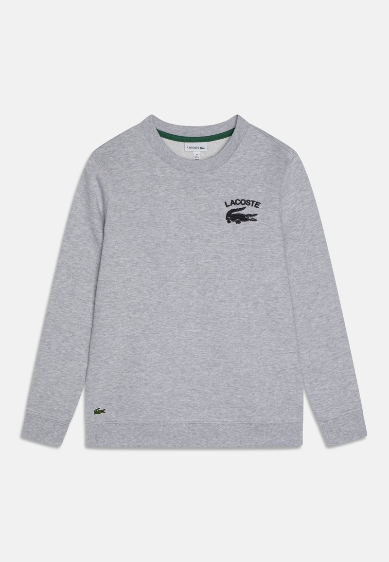 Sweat-shirt gris clair à manches longues avec col rond, logo Lacoste noir et emblème de crocodile sur la poitrine, ainsi qu'un petit emblème de crocodile vert près de l'ourlet.