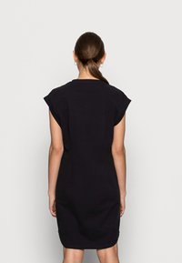 Robe noire à manches courtes avec une coupe décontractée, col rond et épaules sans coutures, fabriquée dans un tissu doux, de longueur jusqu'aux genoux.