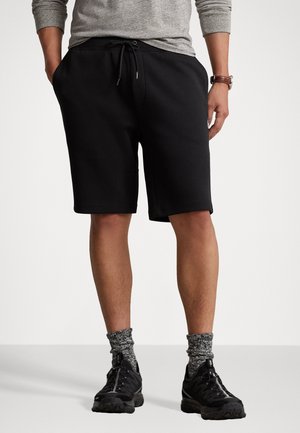 Zwarte shorts van een katoenmix met een elastische tailleband met trekkoord, steekzakken aan de zijkant en een comfortabele pasvorm, gecombineerd met zwarte sneakers en gemêleerde sokken.