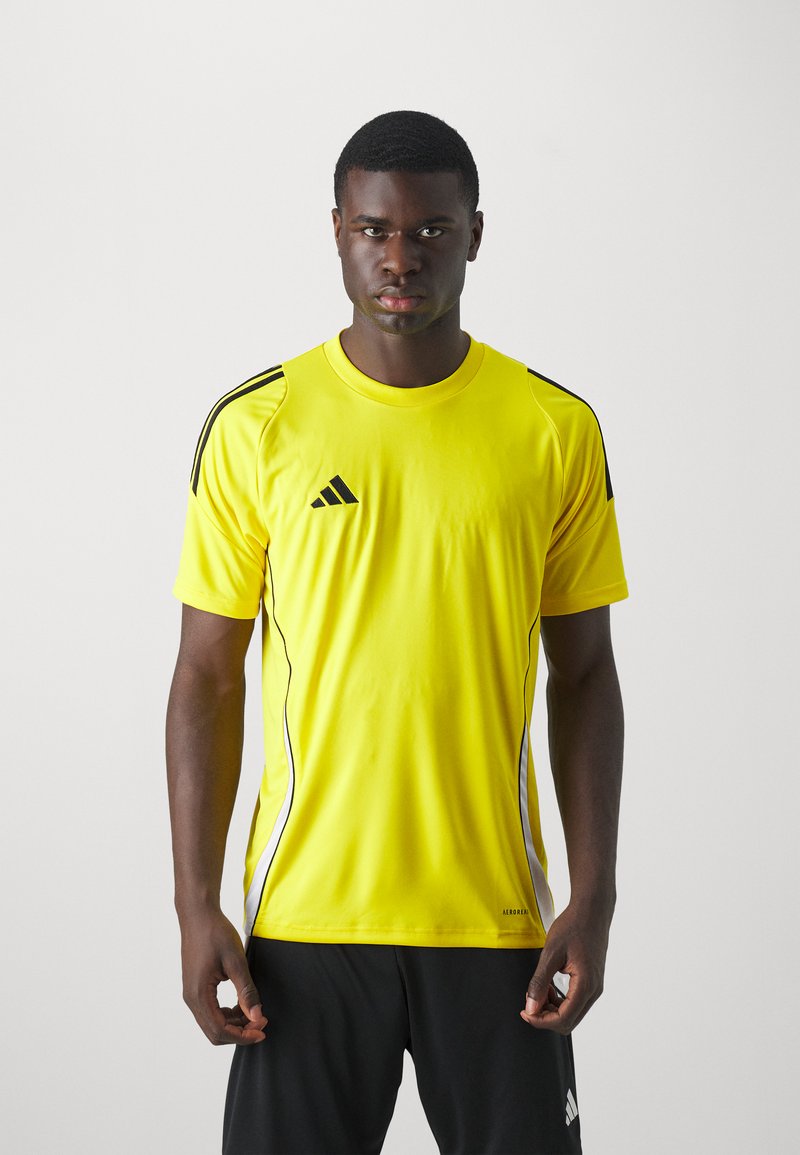 T-shirt de sport jaune avec des accents noirs et le logo Adidas. Manches courtes, col rond et design à panneaux latéraux avec des détails blancs.
