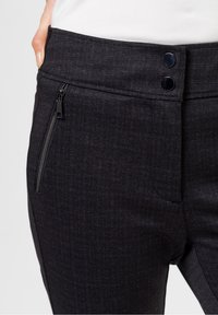 Pantaloni neri con texture, caratterizzati da una cintura liscia, due bottoni e una tasca con cerniera sul lato.