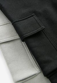Twee gevouwen sweater in zwart en lichtgrijs. De stof is zacht en textuur met geribde boorden. Strakke lijnen en geen zichtbare patronen.