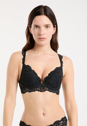 Schwarzes Spitzen-Bralette mit tief ausgeschnittenen Cups, gezackten Kanten und breiten Trägern. Verfügt über ein Blumenmuster und einen transparenten Spitzenbund.