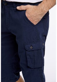 Lautan celana cargo yang terbuat dari kain ringan, dilengkapi dengan saku samping yang memiliki penutup kancing dan pinggang klasik untuk pas yang aman.