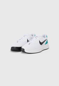 Hvide sportssko med en tekstureret overdel, sort Nike swoosh og teal detaljer på hælen. Har en sort gummisål for traction.