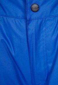 Bright blue fabric with a smooth texture. Features a black button with an embossed logo, stitched seams, and a sleek design.