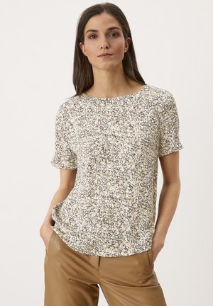 Blusa a maniche corte con stampa floreale in tessuto morbido, caratterizzata da un collo rotondo e una vestibilità ampia. I colori includono beige, crema e tonalità di marrone delicato.