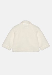 Kremowa kurtka z futra sztucznego z kołnierzykiem, krótkim krojem i szerokimi rękawami. Posiada miękką teksturę i proste szwy wzdłuż krawędzi.