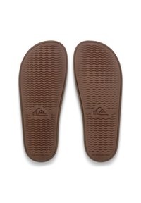 Semelles de tongs en caoutchouc marron avec une surface texturée présentant des rainures horizontales et un logo Quiksilver embossé près du talon.