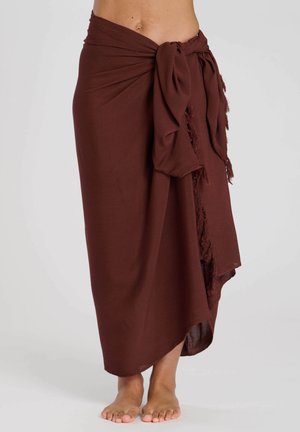 Jupe enveloppante marron textured avec des bords effilochés et une ceinture à la taille, présentant un design fluide et une coupe jusqu'aux chevilles.