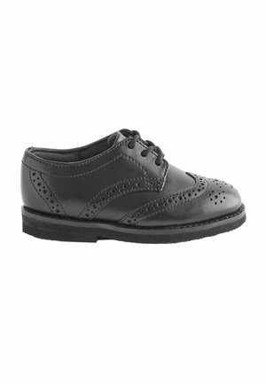 Chaussure noire en cuir à lacets avec des détails de brogue, bout arrondi et surface texturée. Semelle en caoutchouc plate avec un léger talon, design classique.