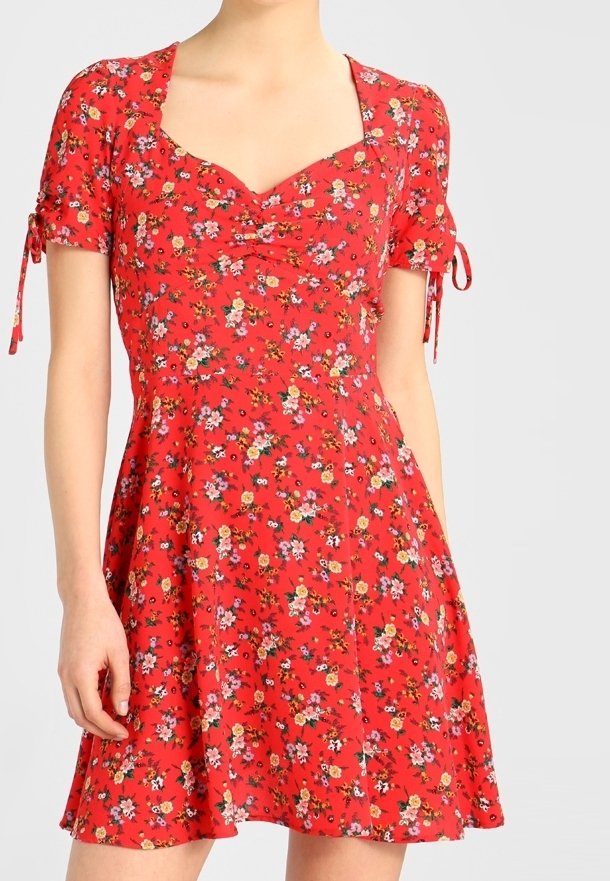 Rotes Blumenkleid mit quadratischem Ausschnitt, kurzen Ärmeln und Bindebändern. Weicher Stoff, ausgestellter Rock mit einem mehrfarbigen Blumenmuster.