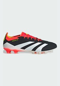Scarpa da calcio nera con strisce bianche, lacci rossi e dettagli rossi. Presenta un design elegante, una parte superiore testurizzata e una suola in gradiente da rosso a bianco.
