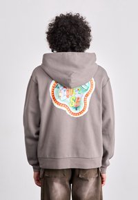 Grey hoodie made of cotton with a large, colorful embroidered design on the back. Features a kangaroo pocket and ribbed cuffs.