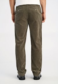 Corduroy broek in olijfgroen met getextureerde verticale strepen, voorzien van achterzakken met metalen knopen en een taps toelopend ontwerp van de pijpen.