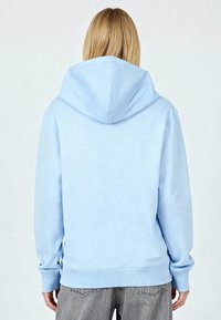 Felpa con cappuccio in cotone azzurro chiaro, dotata di tasca a marsupio, polsini e orlo a coste. Presenta un cappuccio affusolato e una texture morbida e liscia.