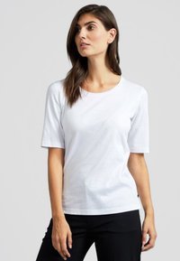 T-shirt bianco a maniche corte realizzato in morbido cotone, caratterizzato da un collo rotondo e una vestibilità rilassata. Texture liscia senza schemi o accenti.