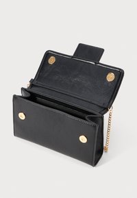 Black faux leather handbag with a chain strap, featuring gold snap closure, multiple compartments, and a textured surface. Inside is lined and spacious.