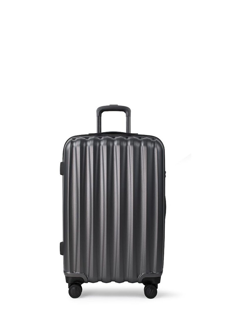 Czarna, twarda walizka z pionowymi żłobieniami, z teleskopowym uchwytem i czterema obrotowymi kółkami, stojąca w pionie na białym tle.
