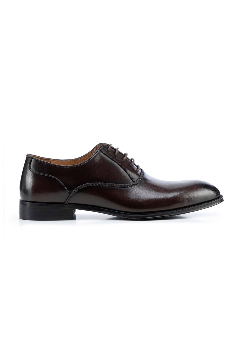 Zapato de vestir de cuero marrón con un acabado suave, punta redondeada, tacón bajo y detalle de cordones. Presenta costuras sutiles a lo largo de la parte superior.