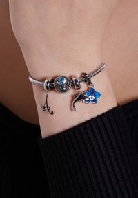 Zilveren armband met verschillende bedels: een dolfijn, een blauwe bloem en de letter 'A'. Heeft getextureerde schakels en gekleurde accenten.