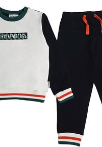 Set di felpa e pantaloni in bianco e nero. La felpa presenta un logo verde e nero, polsini a coste e dettagli a strisce. I pantaloni hanno una vita elastica.