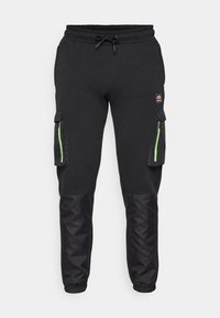 Zwarte sweatpants met cargozakken, groene ritsaccenten en elastische boorden. Gemaakt van een zachte stof met contrasterende, gestructureerde panelen op de benen.