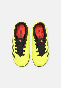 Zapatos de fútbol amarillos brillantes con rayas y cordones negros, diseño texturizado y plantillas de acento rojas, con un collar acolchado para mayor comodidad.