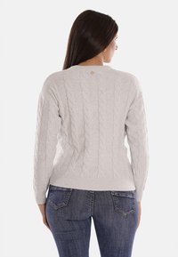 Maglione grigio chiaro a maglia cable con scollo rotondo, polsini e orlo a coste, con dettagli di luccichio sottili e un piccolo logo sul retro.