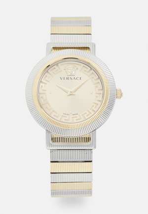 Auksu ir sidabru tonu Versace laikrodis su tekstūruotu apvaliu ciferblatu, Medūzos logotipu, Graikų raktų raštu ir sujungta metaline juosta.