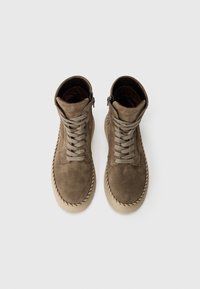 Bottines en suède taupe avec un bout arrondi, dotées d'un laçage à l'avant et d'une fermeture éclair sur le côté, accentuées par des détails tressés le long de la semelle.