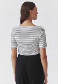 Gestreept T-shirt met korte mouwen in wit en zwart, met een wijd decolleté en een losse pasvorm, gecombineerd met hoge zwarte broek.